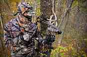 deer hunter in tree stand with bow and arrow